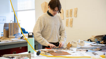 student working with leather at a tabletop