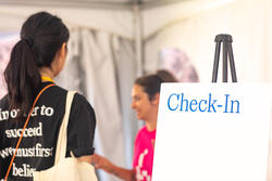 Student standing near a sign that says "check-in"
