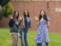 3 students smiling and waving
